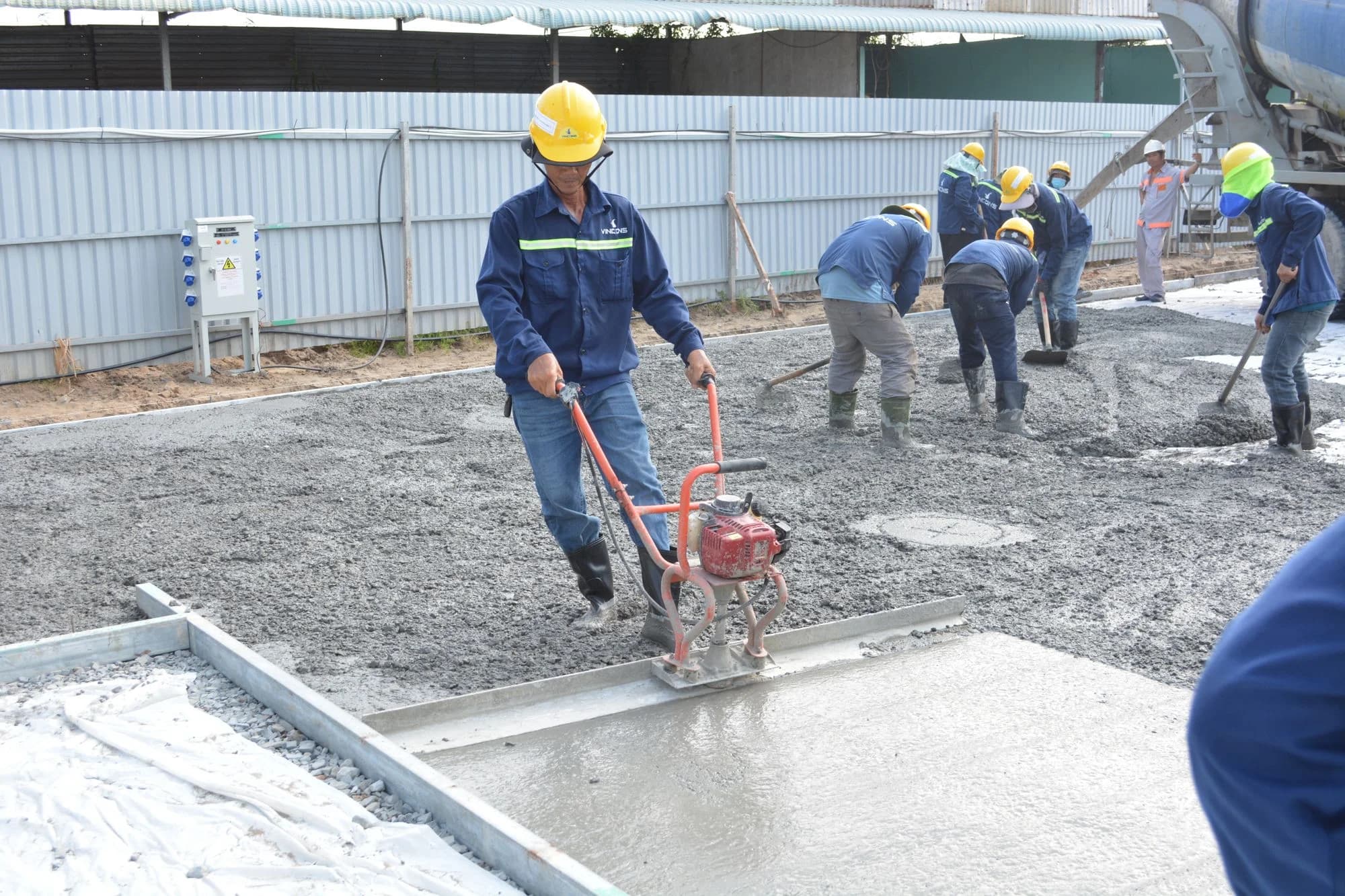 Crew levelling and smoothing freshly poured concrete with a powered screed.