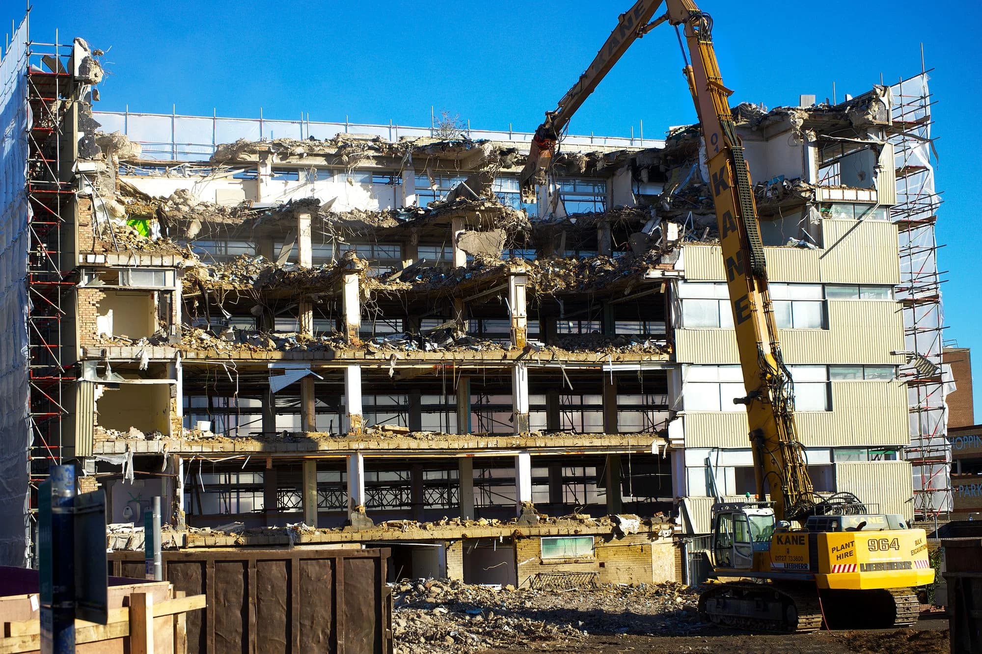 Excavator demolishing a partially dismantled building.