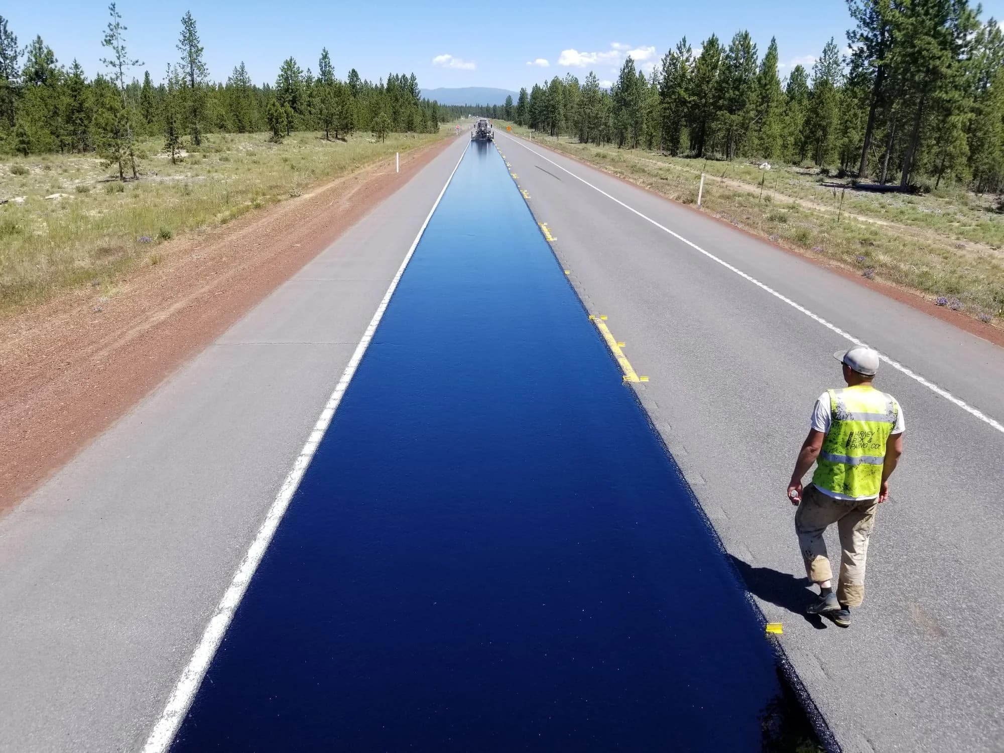 Aerial view of a newly paved rural highway with a road worker.