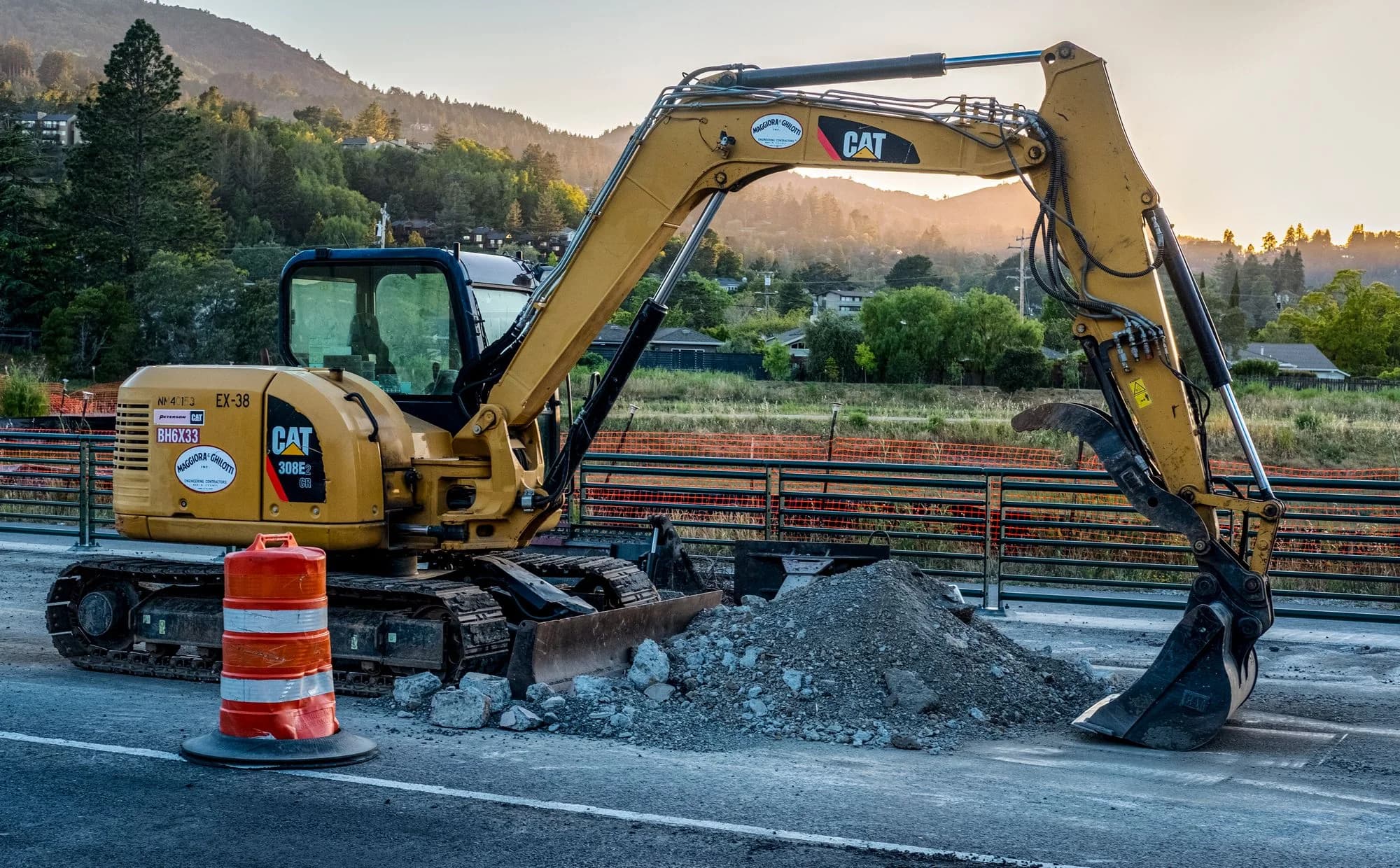 Caterpillar excavator beside a gravel pile at a road construction site.