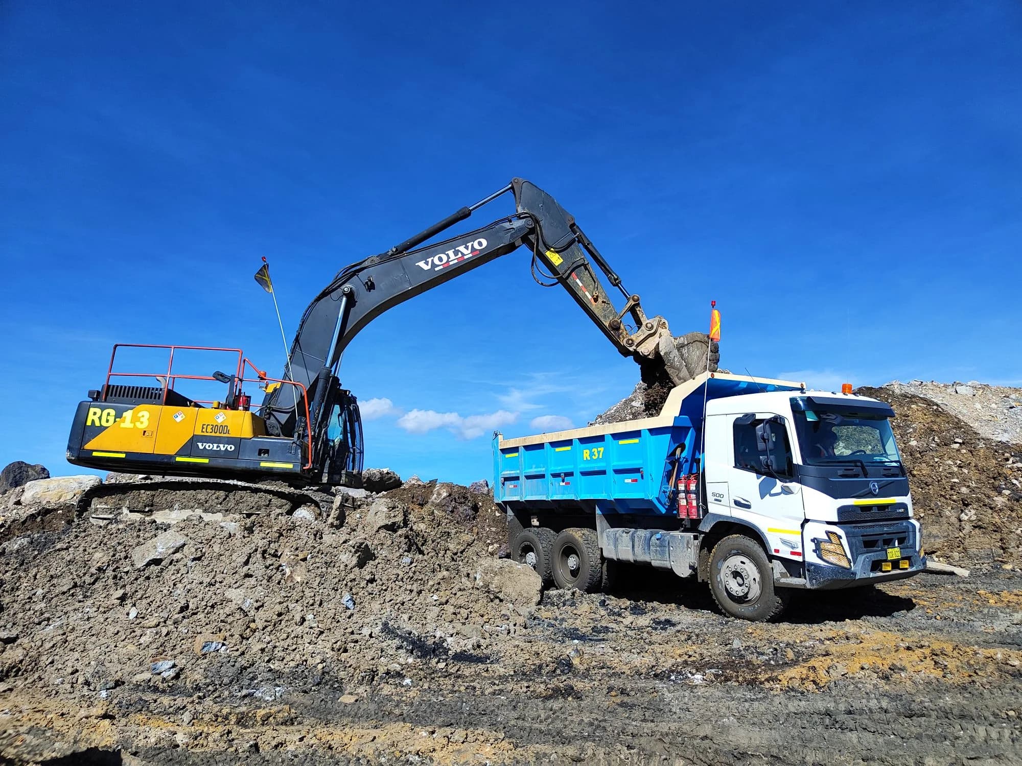 Excavator loading soil into a dump truck at a construction site.